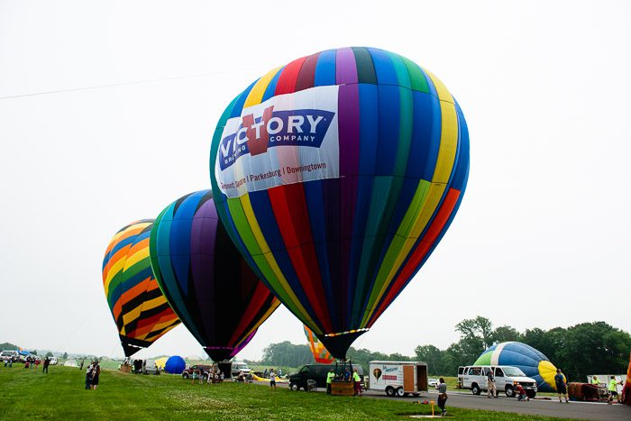 A group of hot air balloons that are in the grass.