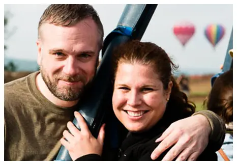 A man and woman are hugging in front of balloons. Used on flight safety page.