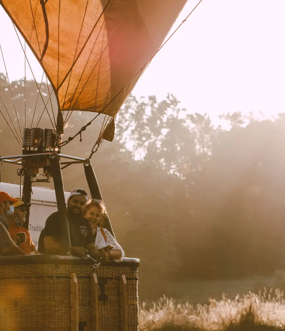 A couple of people are sitting on top of a hot air balloon