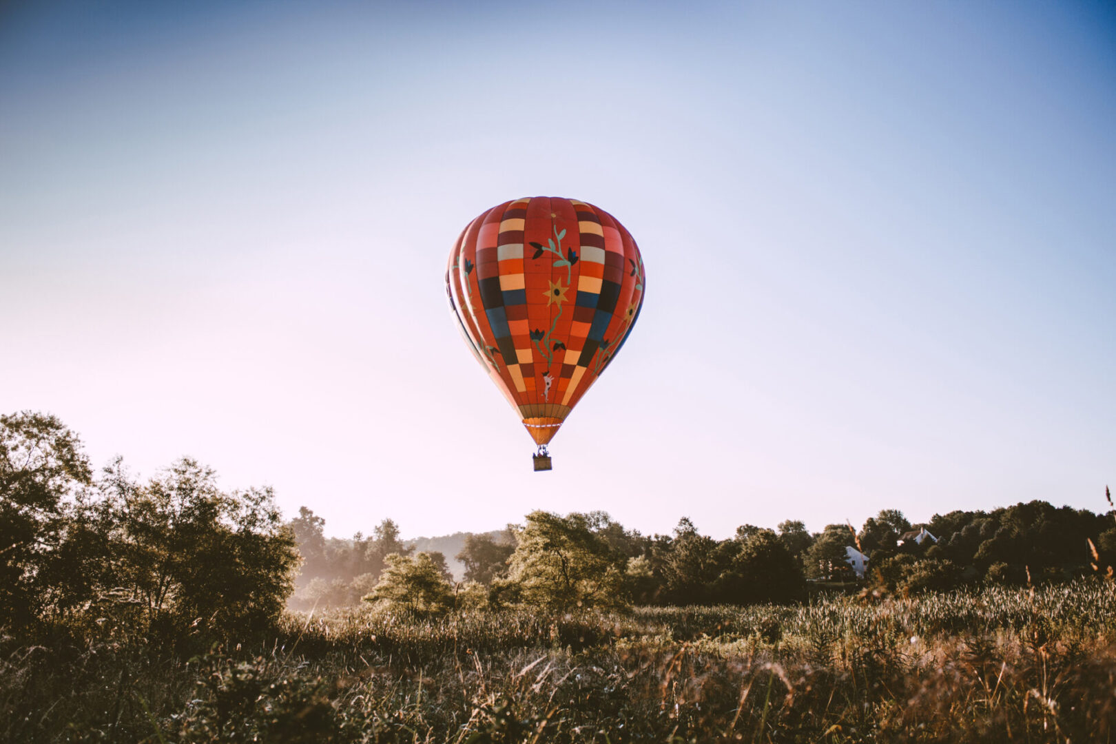 A hot air balloon flying over the grass.