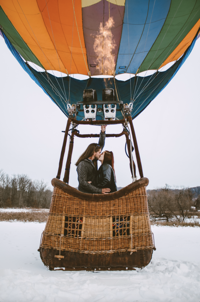 Two people are kissing in a hot air balloon.