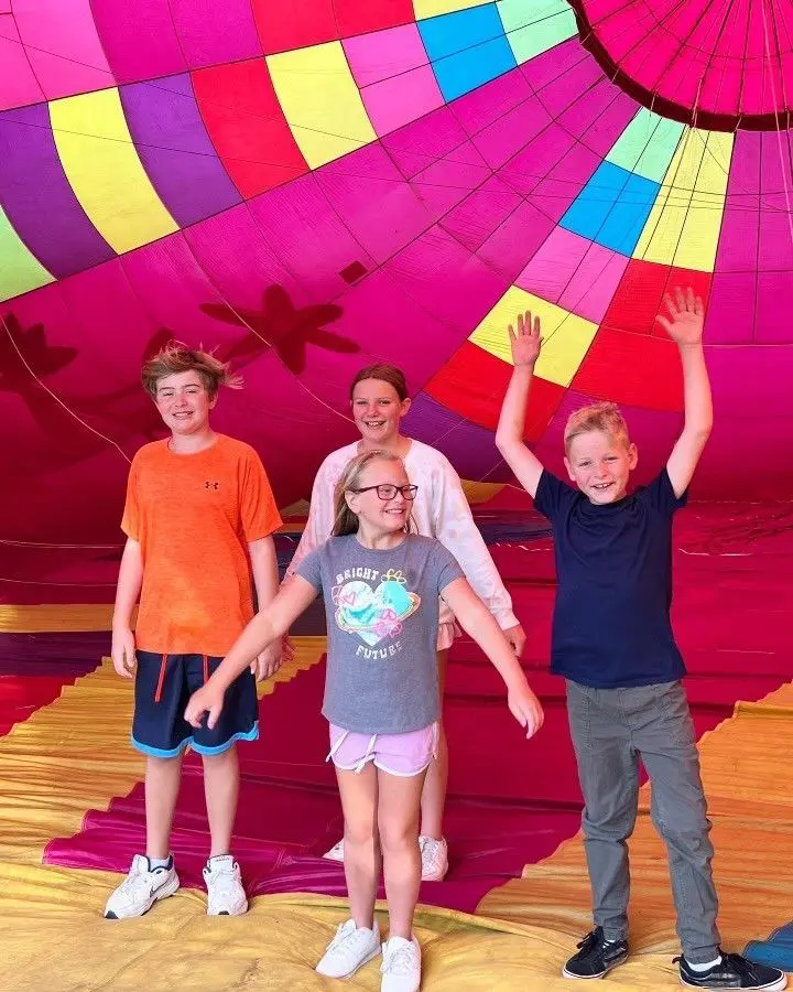 A group of people standing in front of a hot air balloon.